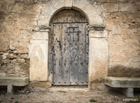 Picture of Ancient wooden door on a stone made wall and cement benches